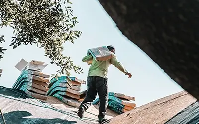 Man carrying shingles on roof